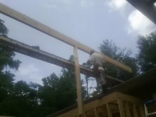 Carpenter setting a ridge beam over a new addition frame — Ice Dam Removal by Roofing Brothers in Hunker