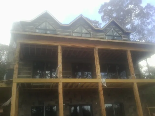 Dormers and porch framing on a large log home under construction — Roof Coating work by our crew in Hunker