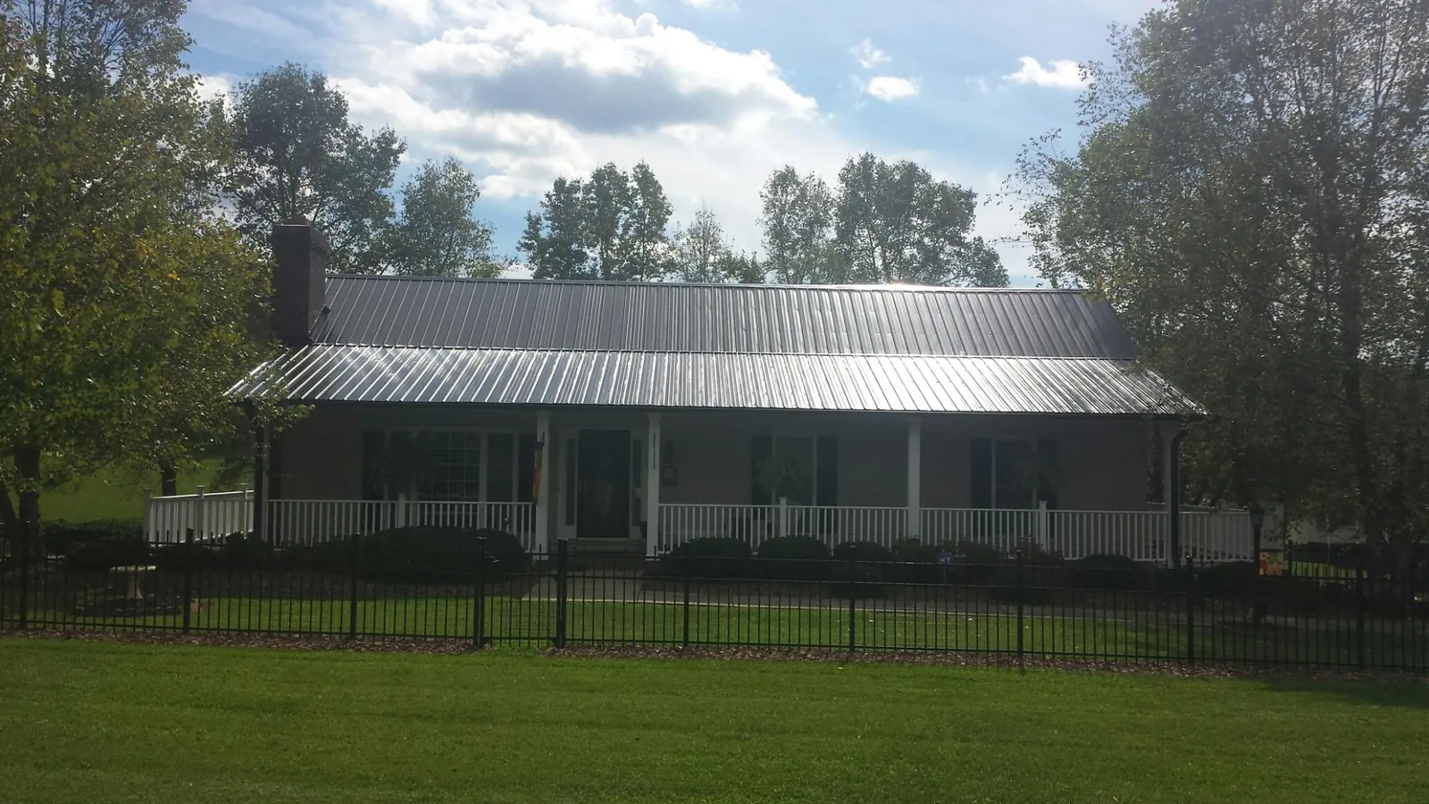 Gray metal roof on a brick ranch with a full width front porch — Gutter Guard Installation work by our crew in Hunker