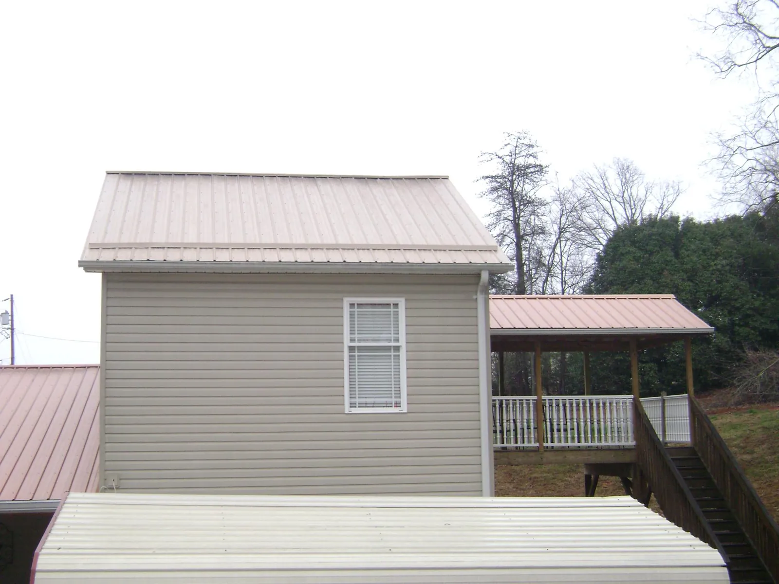 Tan metal roofs on a two story addition and attached porch, from a Roof Replacement job in Hunker