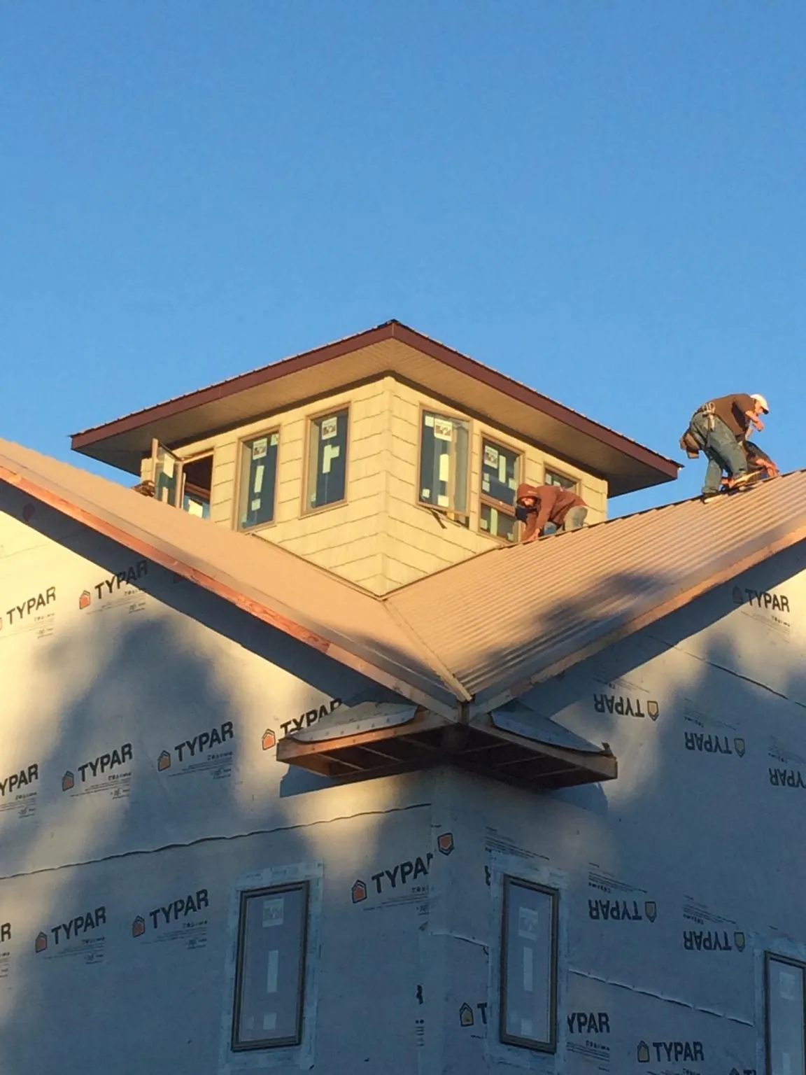 Roofers working around a rooftop cupola on a new metal roof at sunset — Roof Waterproofing in Hunker by Roofing Brothers